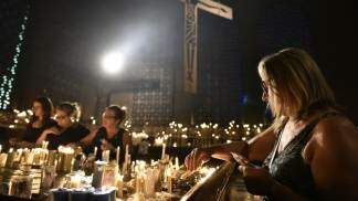 mulher acendendo vela na Capela das Velas do santuário nacional