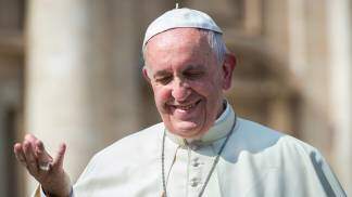 Papa Francisco sorrindo com a mão direita aberta