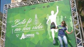 Atleta feliz e acenando na frente do painel da Corrida Mãe Aparecida Atleta feliz e acenando na frente do painel da Corrida Mãe Aparecida