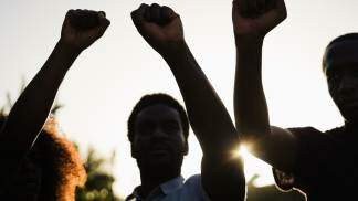 Racismo - pessoas negras com os braços levantados em sinal de protesto