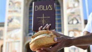 Mão entrega pão e Bíblia