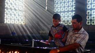 Pai e filho acendendo velas no Santuário