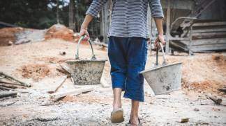 criança carregando baldes em obra
