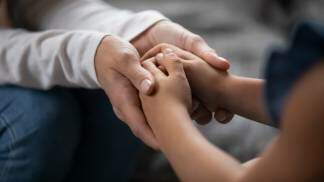 adulto segurando as mão de uma criança