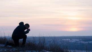 Homem rezando na montanha