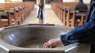 pessoa molhando a mão com água benta dentro da igreja