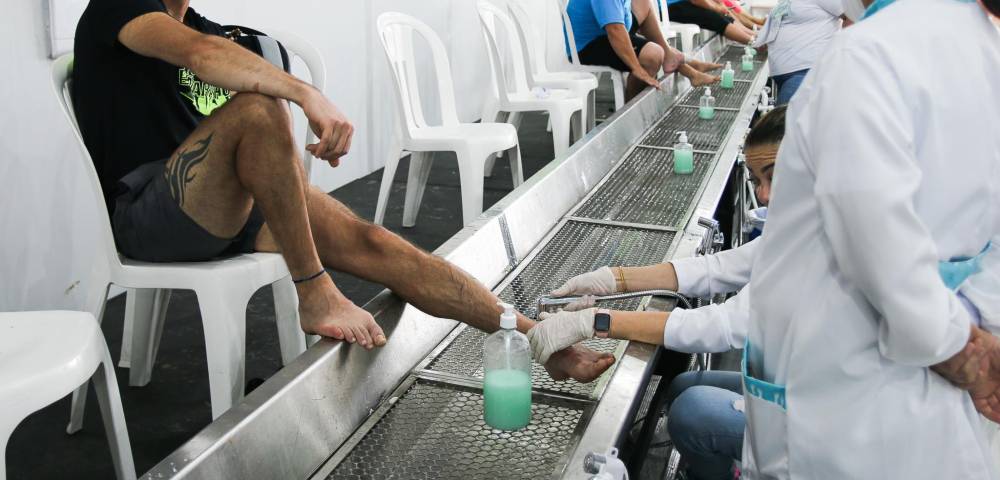 peregrino sorrindo enquanto voluntária higieniza seus pés