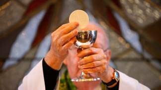 padre levantando a hóstia durante missa