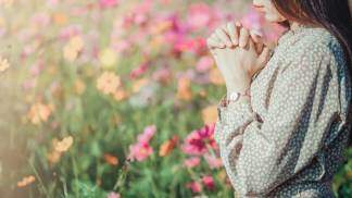 mulher rezando em meio às flores