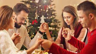 Família rezando de mãos dadas na ceia de natal