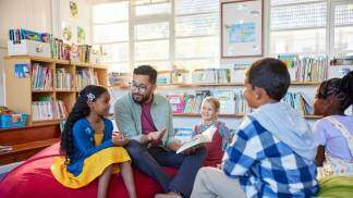 Crianças aprendendo em uma biblioteca com o professor