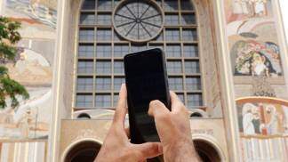 mãos mexendo no celular em frente ao santuário nacional