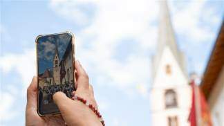 Mão segurando celular fotografando igreja
