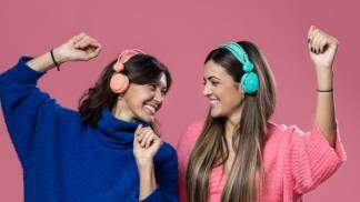 duas moças dançam felizes se olhando com o fone de ouvido na cabeça - imagem utilizada para o almanaque da rádio aparecida