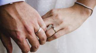 casal de mãos dadas exibindo aliança de casado