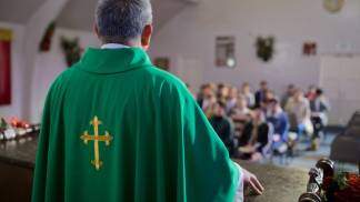 padre com casula verde de frente para o povo na igreja