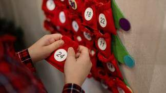 mãos de uma criança segurando um saquinho vermelho com o numero 24 escrito