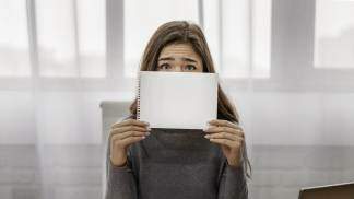 empresaria cobrindo o rosto com um bloco de notas