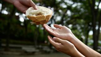 mão entregando pão para uma mão vazia