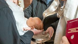 bebê sendo batizado com a água na cabeça