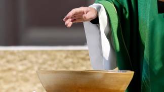 padre abençoando a pia batismal