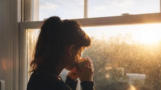 mulher refletindo na janela nascer do sol 