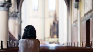 mulher rezando ajoelhada na igreja