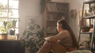 Mulher obesa sentada na cama com feição triste