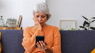 mulher sentada no sofá com celular na mão solidão