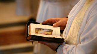 Mãos de um padre com a Bíblia aberta