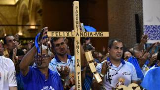 Homens do terço segurando um terço gigante nas mãos