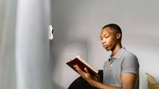 homem estudando na cama lendo a bíblia