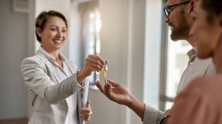 Corretora entregando a chave de um imóvel  ao novo dono