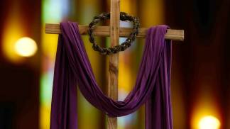 cruz de Cristo com tecido roxo e corda em volta da madeira 
