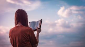 mulher segurando a bíblia de frente para o céu
