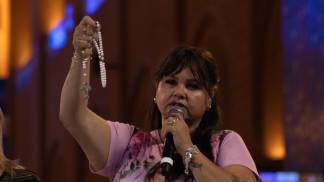 mulher ergue o terço enquanto reza o terço na romaria do terço das mulheres no altar central em 2025