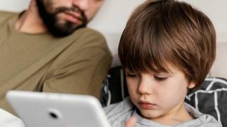 Criança usando tablet ao lado do pai