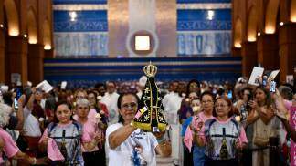 Mulher no Santuário com Nossa Senhora Aparecida nas mãos