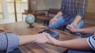 Pessoas de mãos dadas em círculo, sob a mesa um globo e uma bíblia
