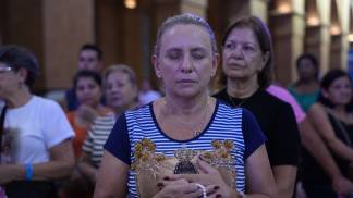 Mulher rezando  com terço na mão