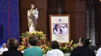 Imagem de são josé no altar central e fiéis de costas rezando