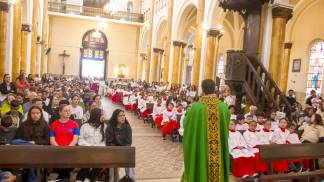 Jovens participando da celebração, padre de costas para a foto