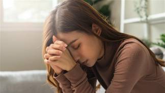 mulher rezando com as mãos entrelaçadas ao rosto