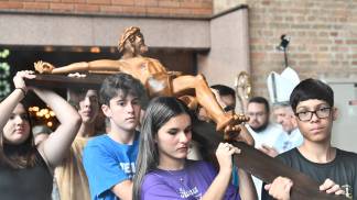 jovens segurando uma cruz em procissão
