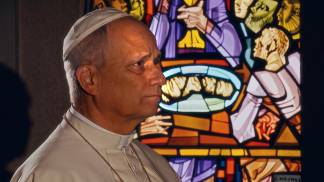 papa em video de intenção de oração de abril sentado em frente a um vitral