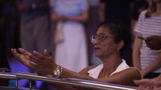 devota ajoelhada com as mãos em oração durante missa do crisma em 2026