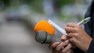 Jornalista com microfone e bloco de notas