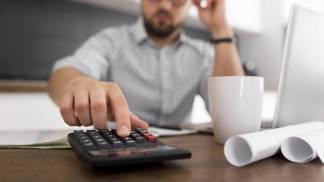 Homem preocupado fazendo as contas na calculadora