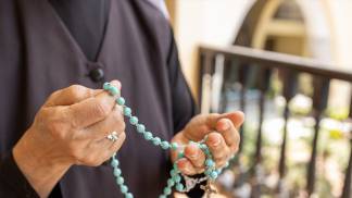 mãos de religiosa segurando terço e rezando