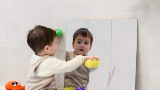 bebê brincando com bolinhas de frente pro espelho
